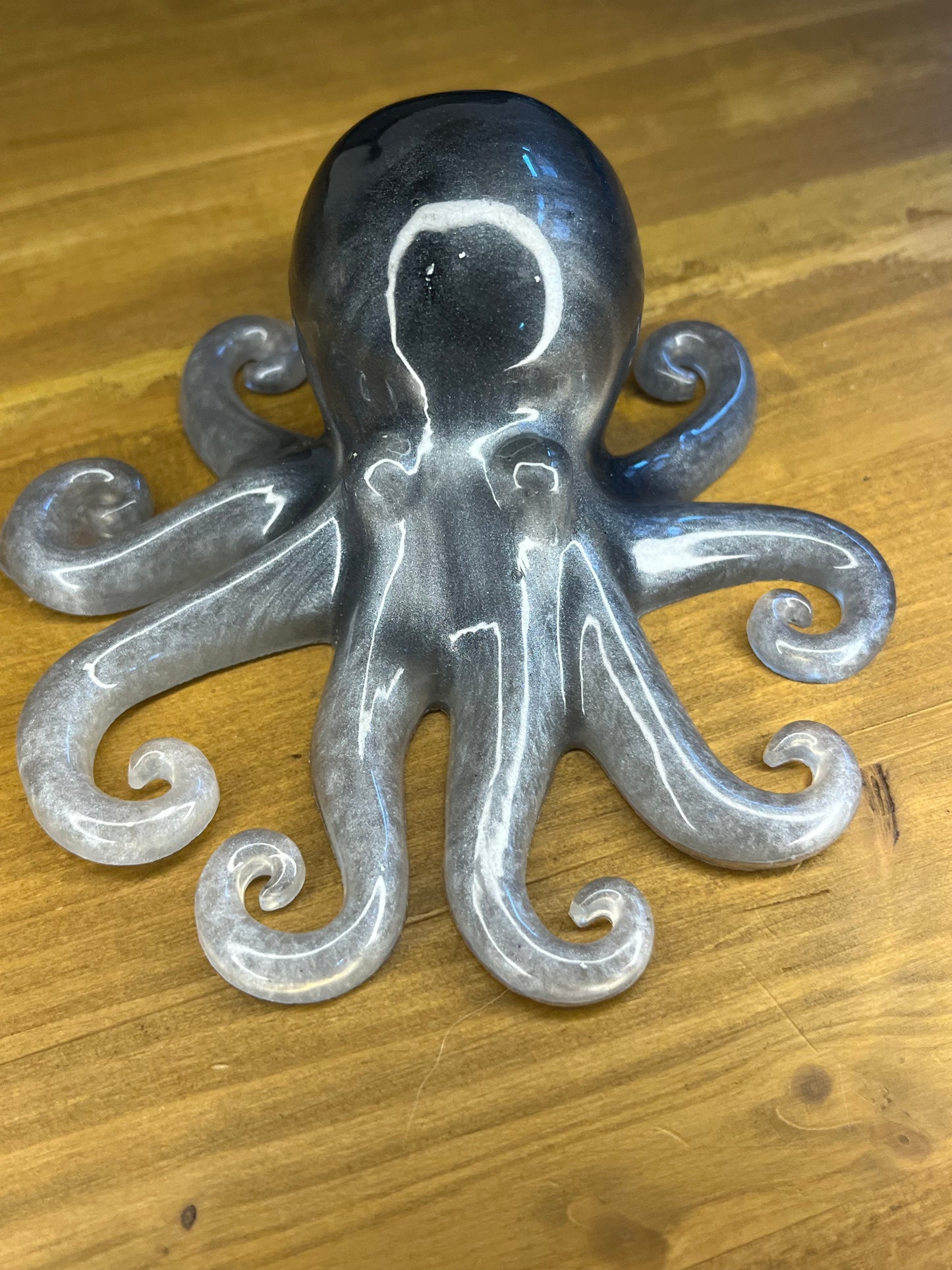 A grey and silver octopus ornament. The sculpture features a rounded head and eight curled tentacles. The colour gradient gives the octopus a shimmering appearance. The figurine is likely made of resin.