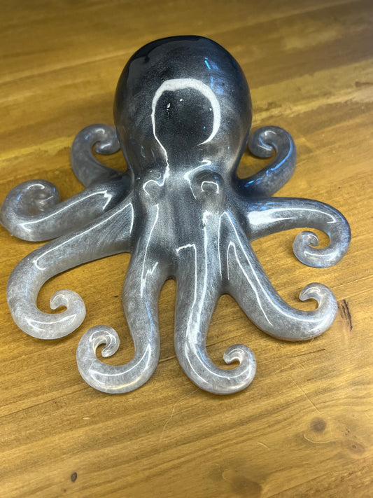 A grey and silver octopus ornament. The sculpture features a rounded head and eight curled tentacles. The colour gradient gives the octopus a shimmering appearance. The figurine is likely made of resin.