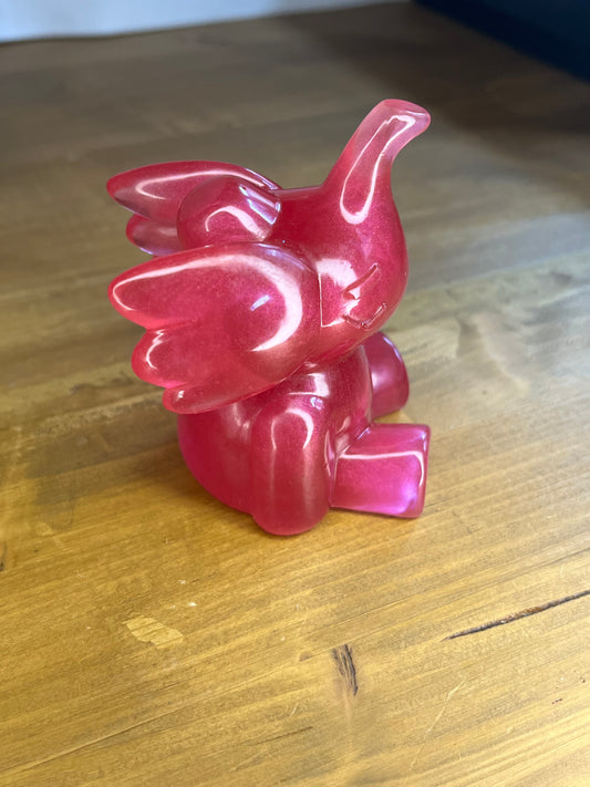 Handmade glossy pink resin elephant ornament displayed on a natural wood surface.
