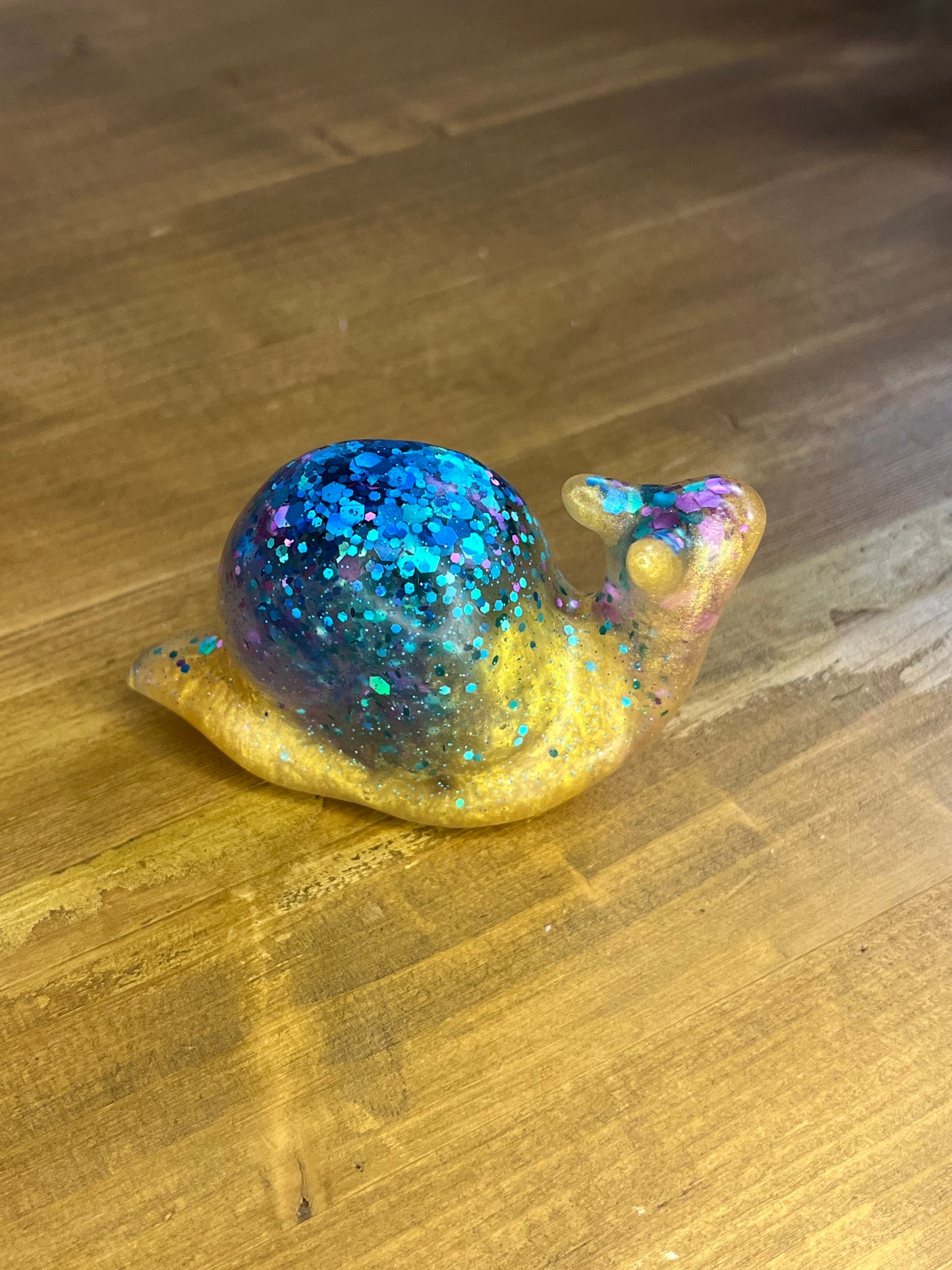 Decorative figurine of a snail with glittery blue body on a wooden surface