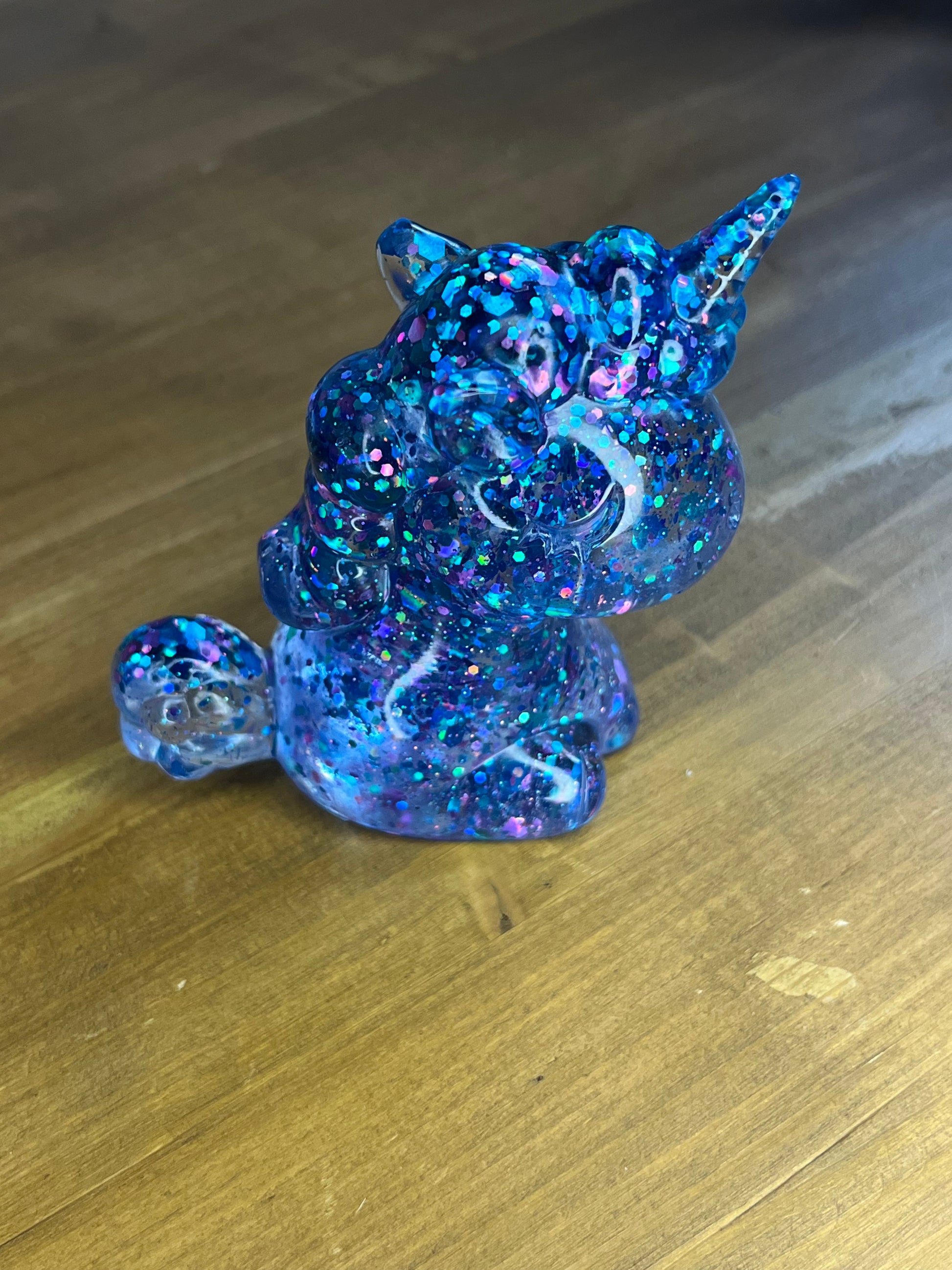 Blue glittery unicorn figurine on a wooden surface