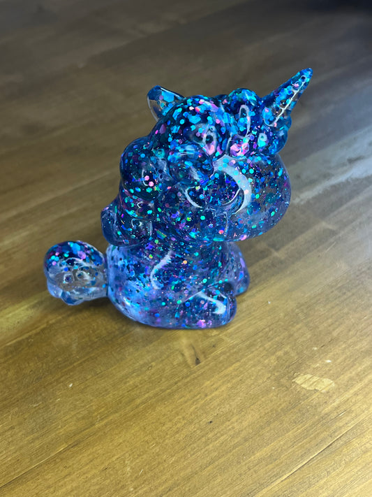 Blue glittery unicorn figurine on a wooden surface