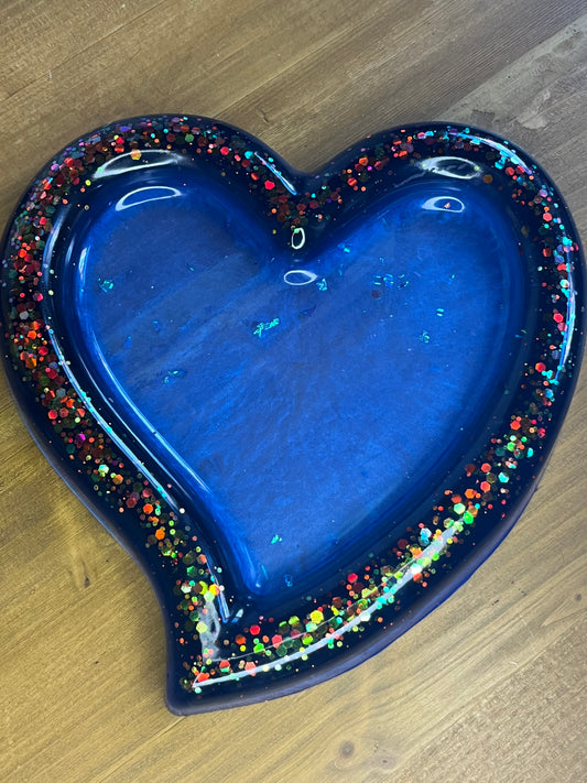 Heart-shaped blue dish with colorful border on a wooden surface
