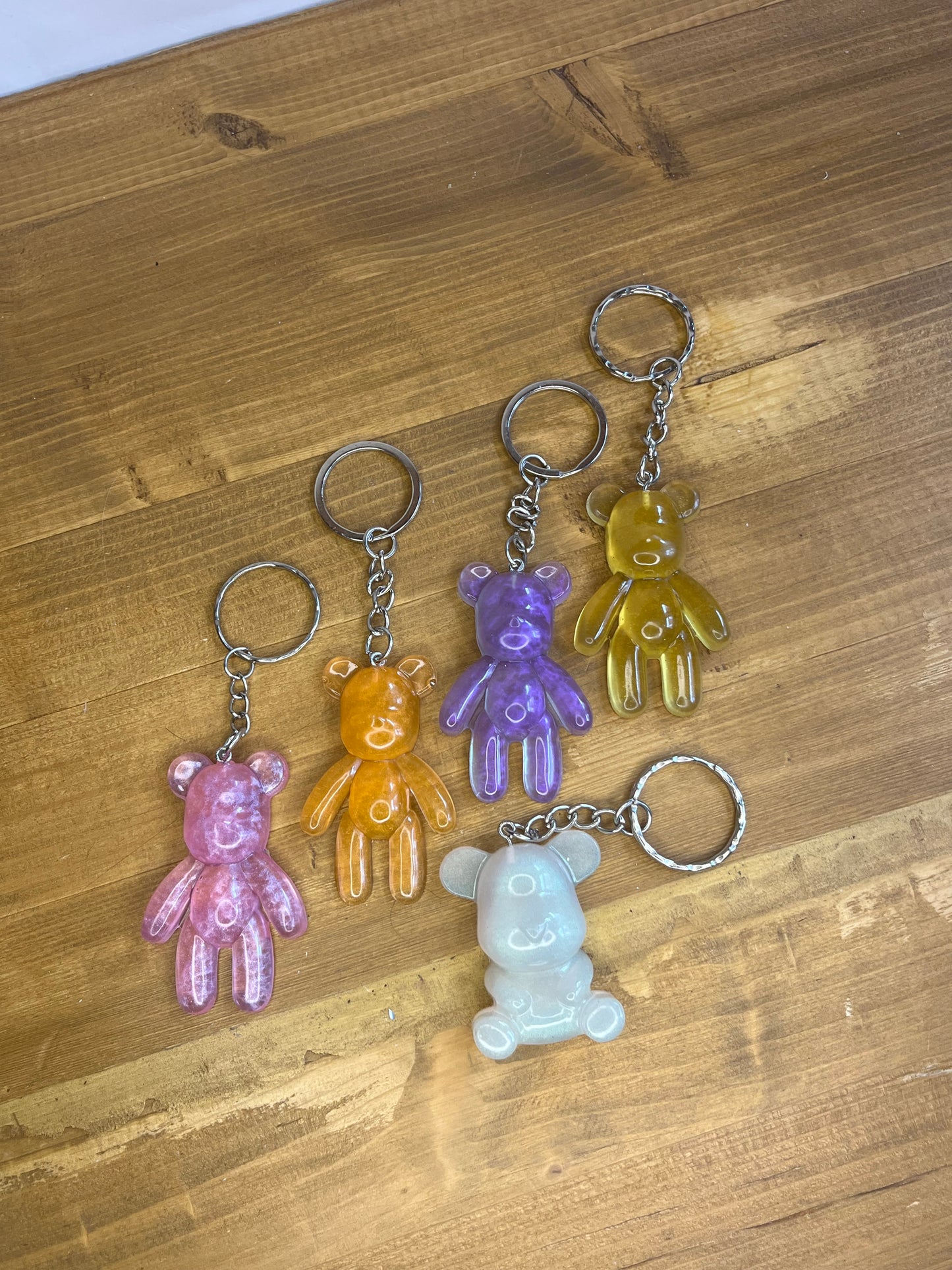 Five colorful bear-shaped keychains on a wooden surface