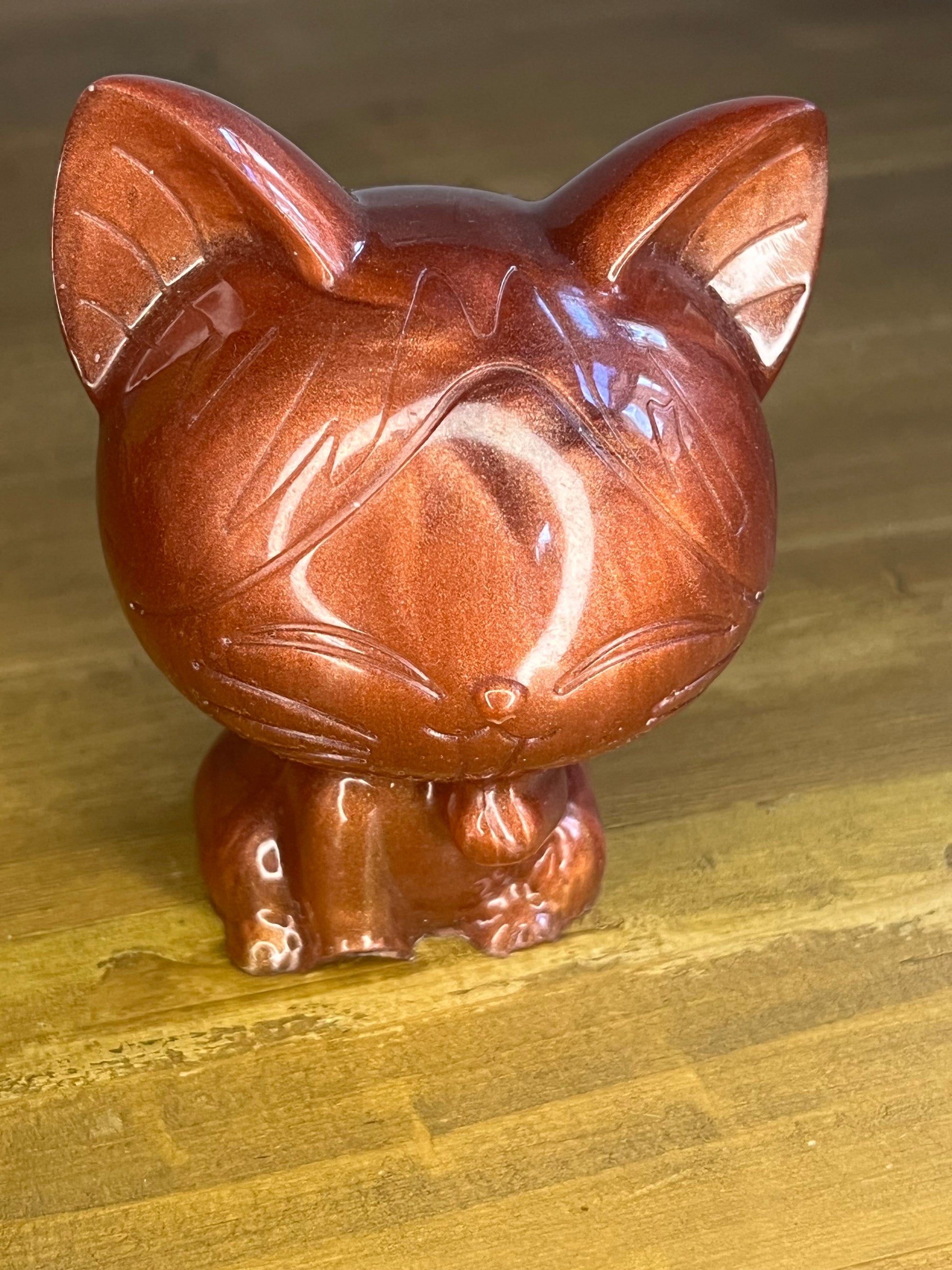 Bronze coloured resin lucky cat on a wooden shelf