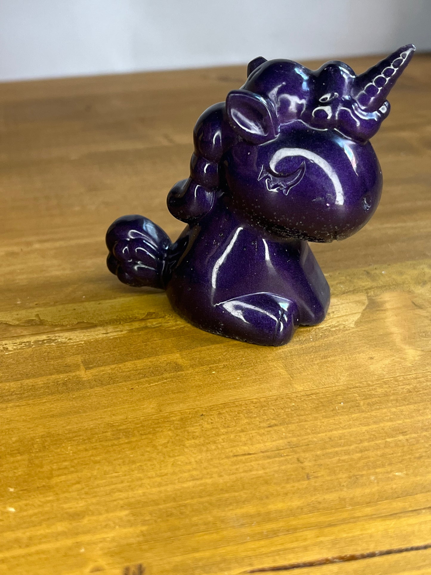 Purple unicorn figurine on a wooden surface