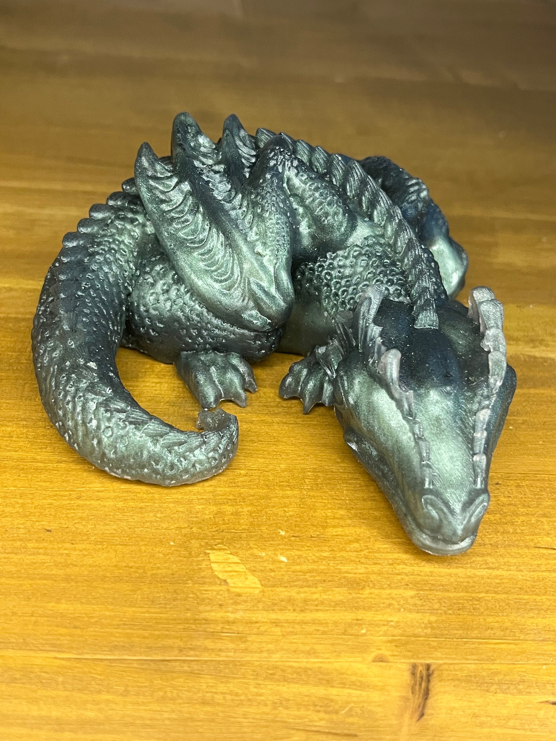 Metallic green dragon figurine on a wooden surface