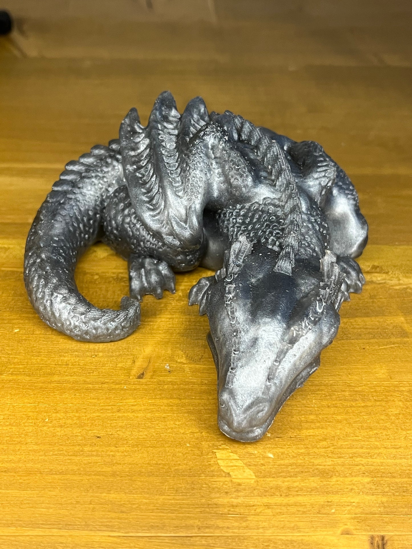 silver sleeping resin dragon curled up on a wooden shelf
