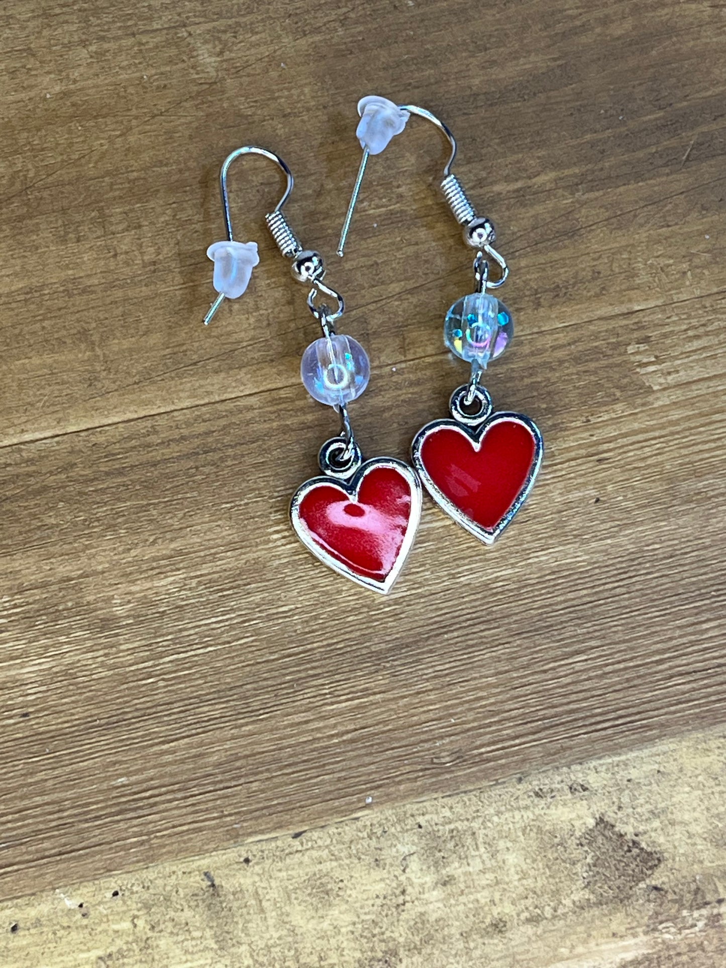 Heart-shaped earrings with clear beads on a wooden surface