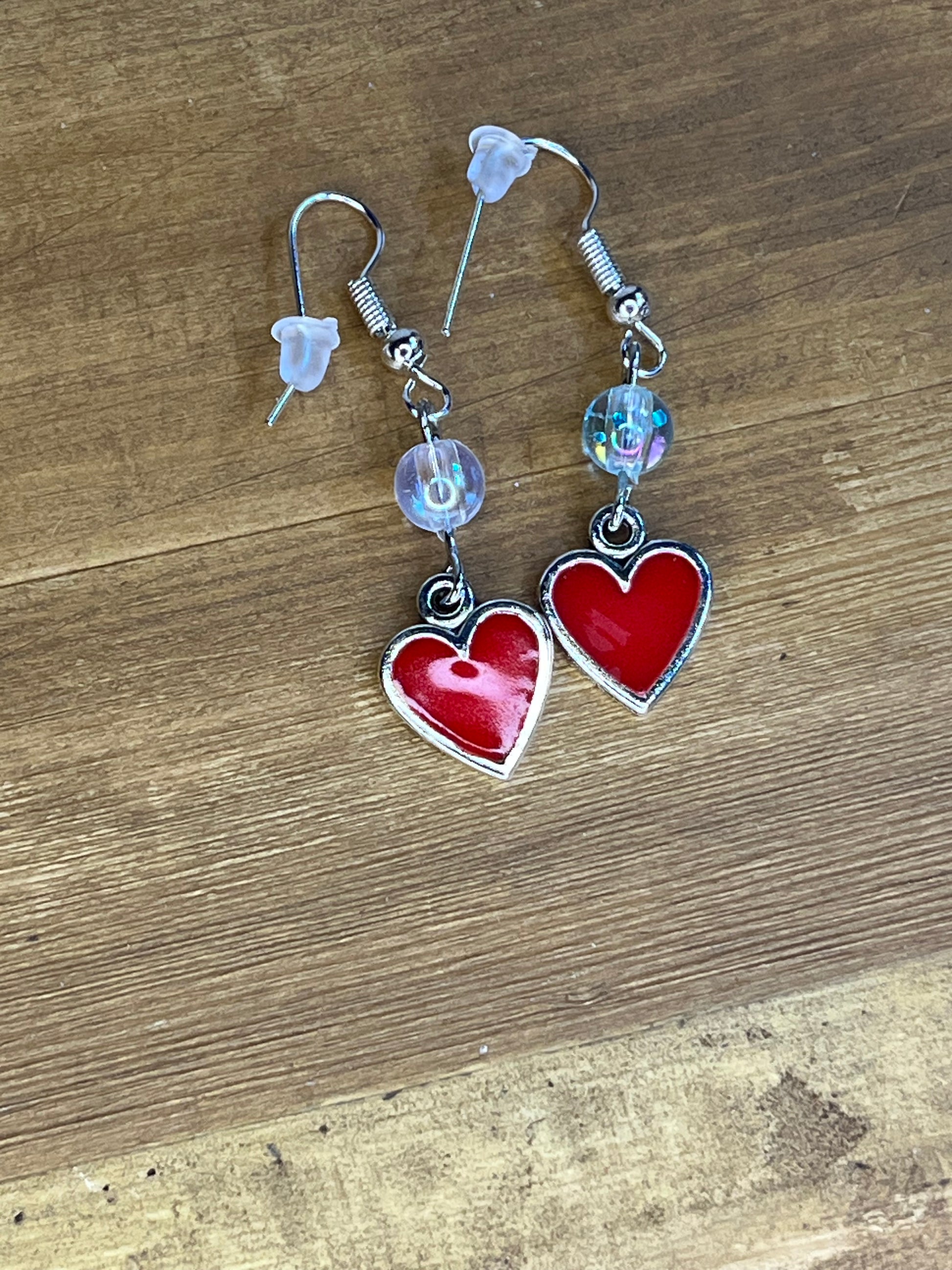 Heart-shaped earrings with clear beads on a wooden surface