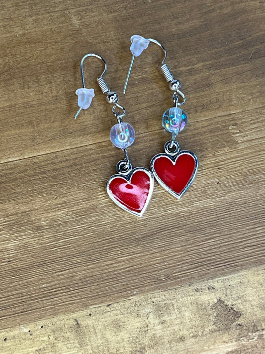 Heart-shaped earrings with clear beads on a wooden surface