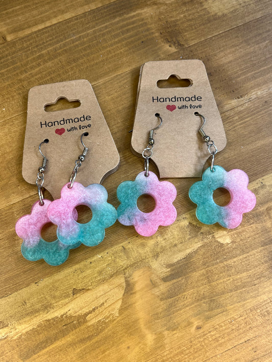 Pair of floral earrings on handmade card packaging on a wooden surface