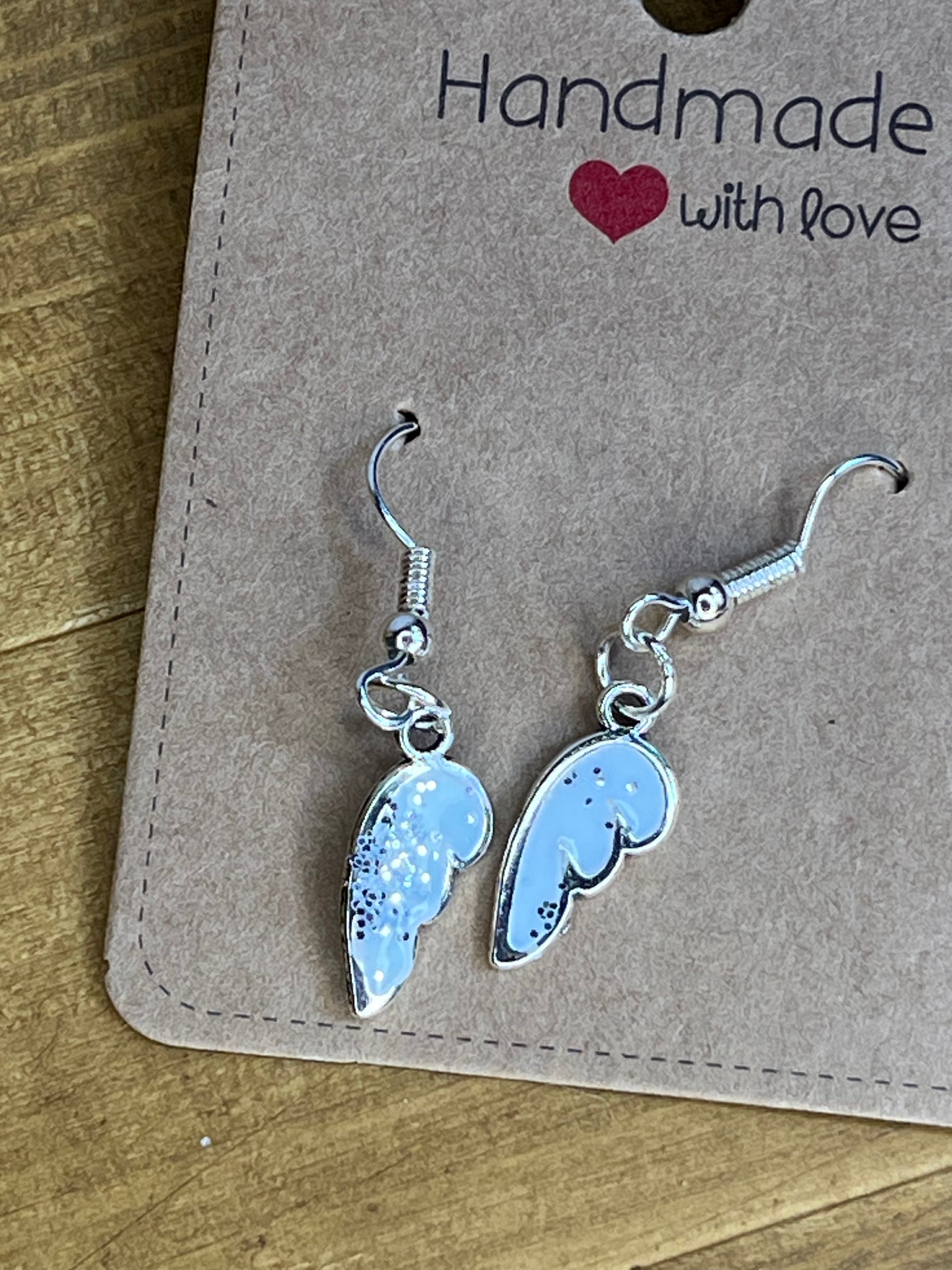 white and silver angel wing -shaped earrings on a 'Handmade with Love' card.