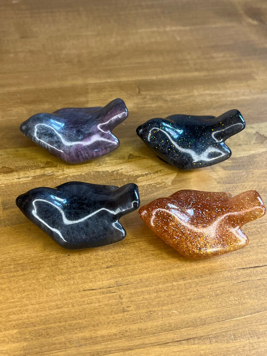 Four resin bird figurines on a wooden surface
