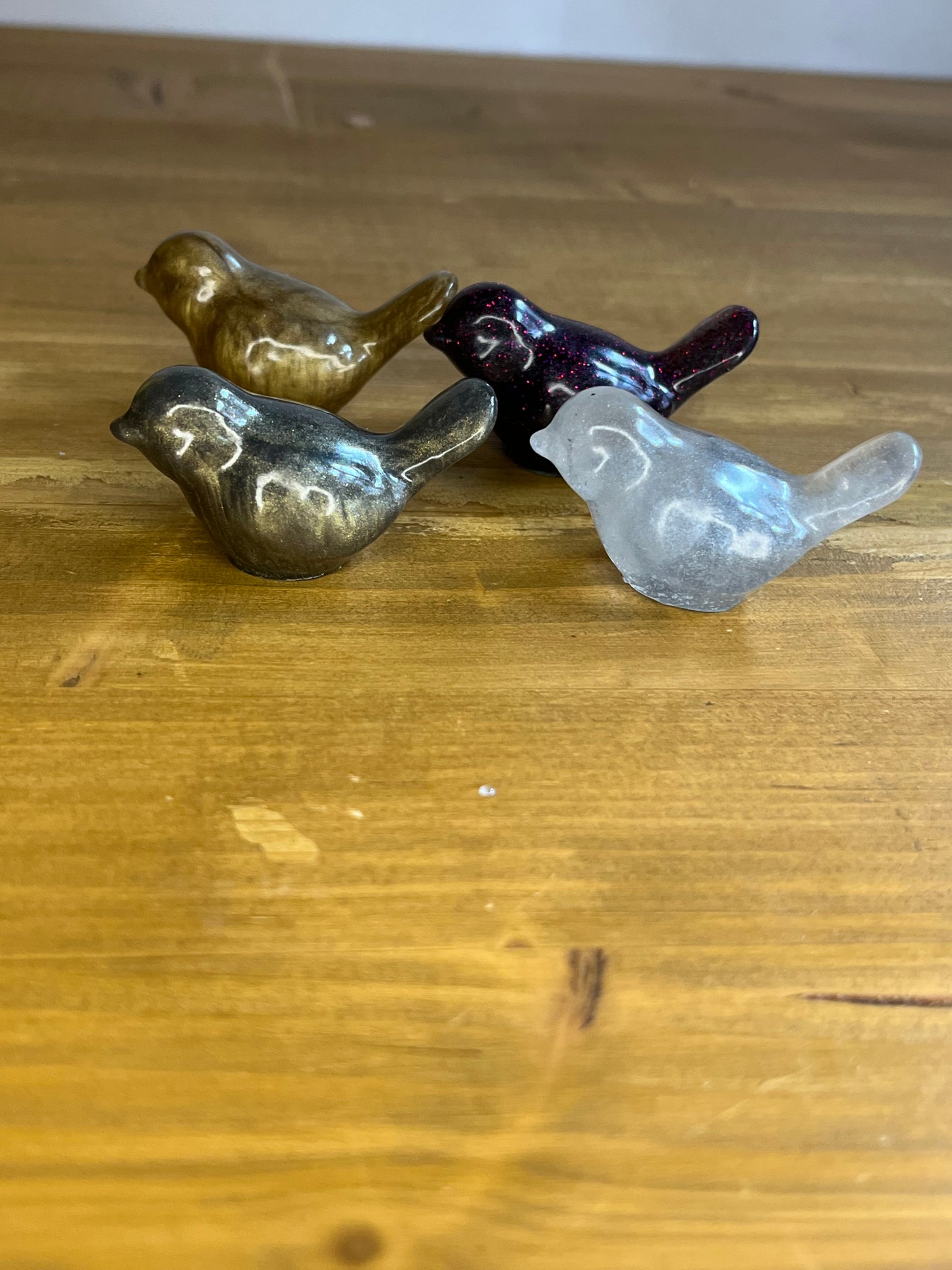 4 resin bird figurines on a wooden surface
