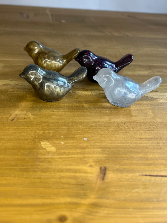 4 resin bird figurines on a wooden surface
