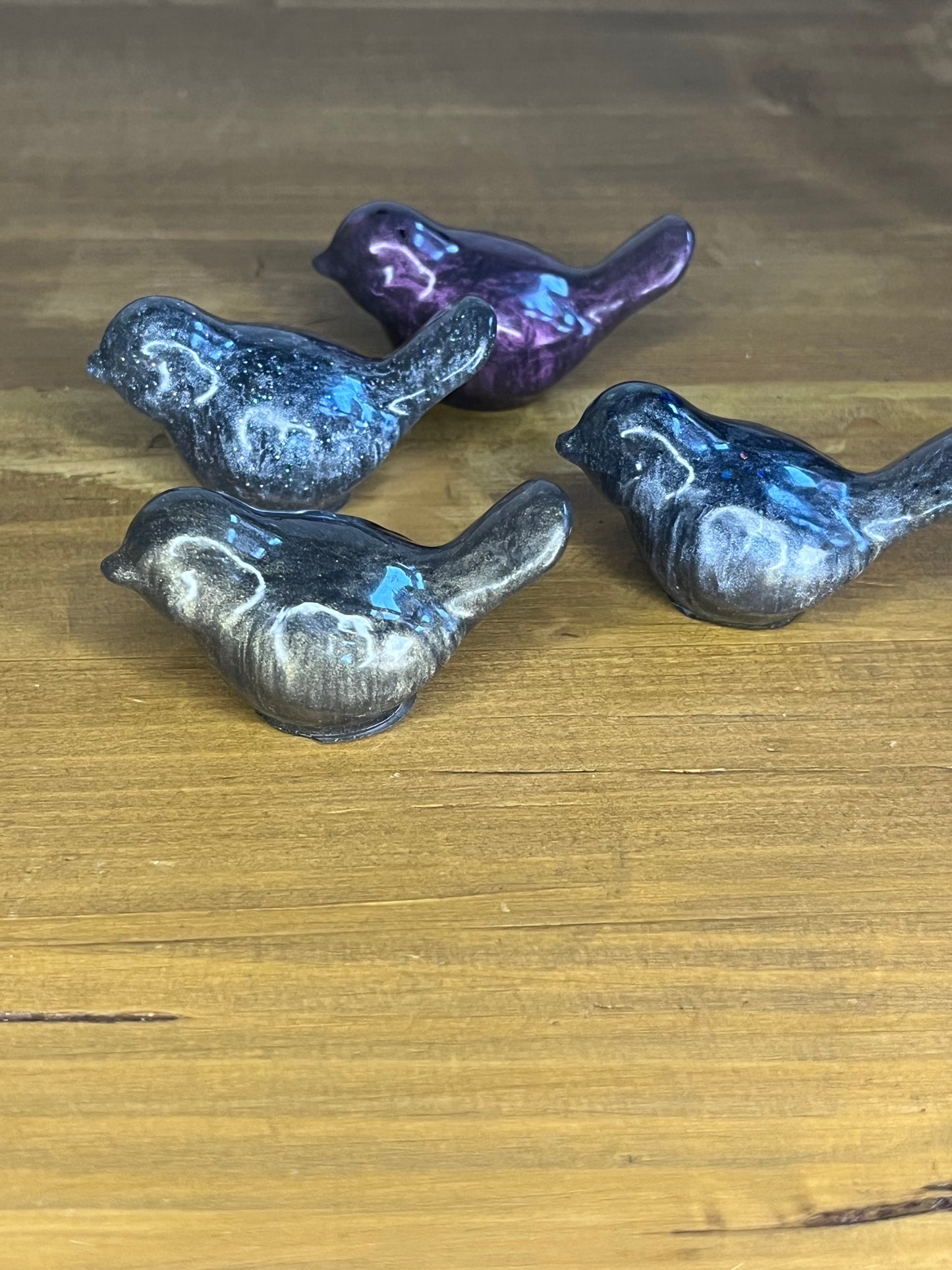 Four resin bird figurines on a wooden surface