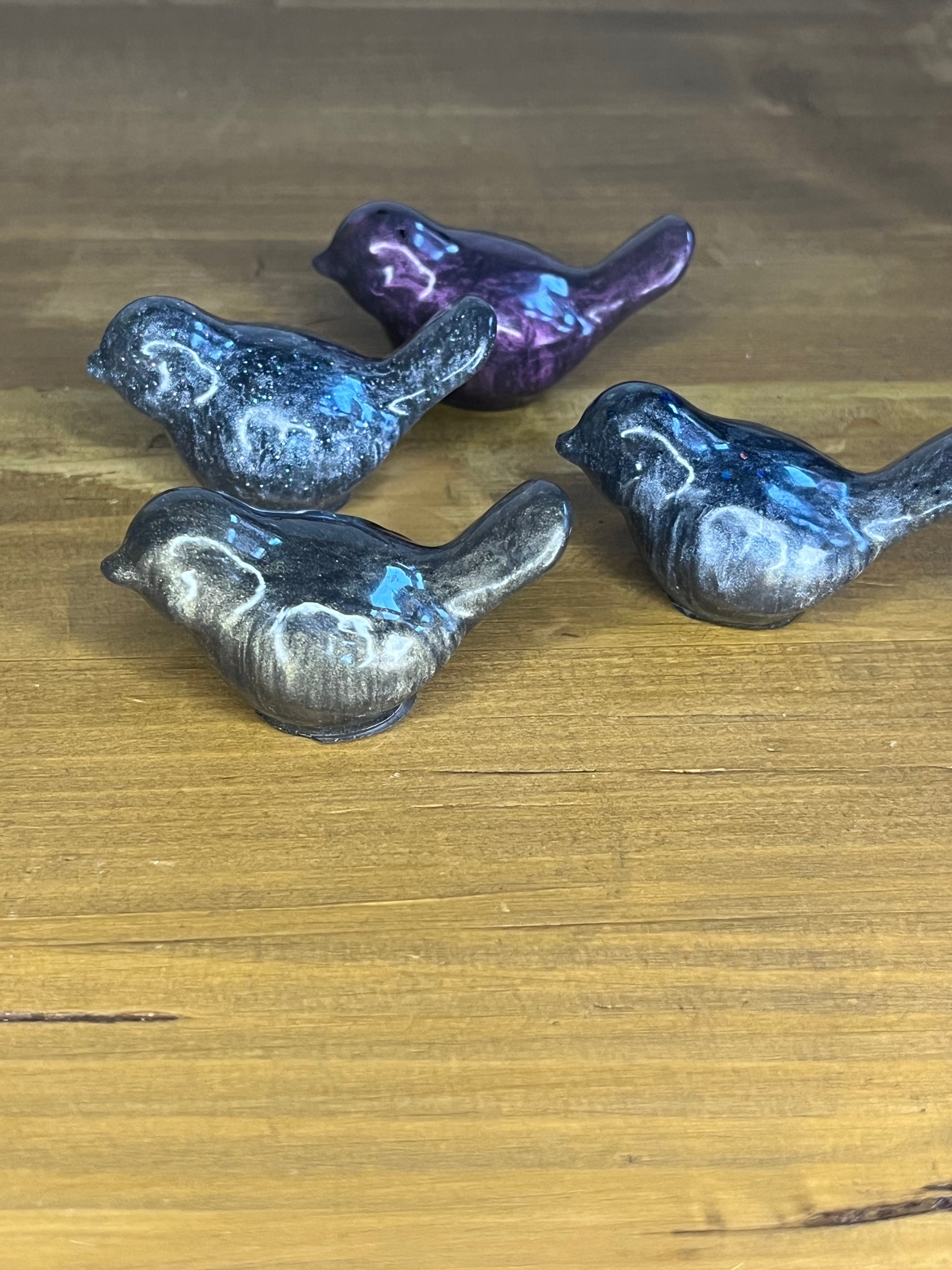 Four resin bird figurines on a wooden surface
