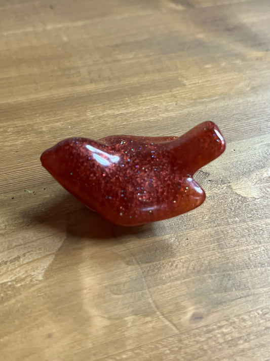 Red glittery bird figurine on a wooden surface