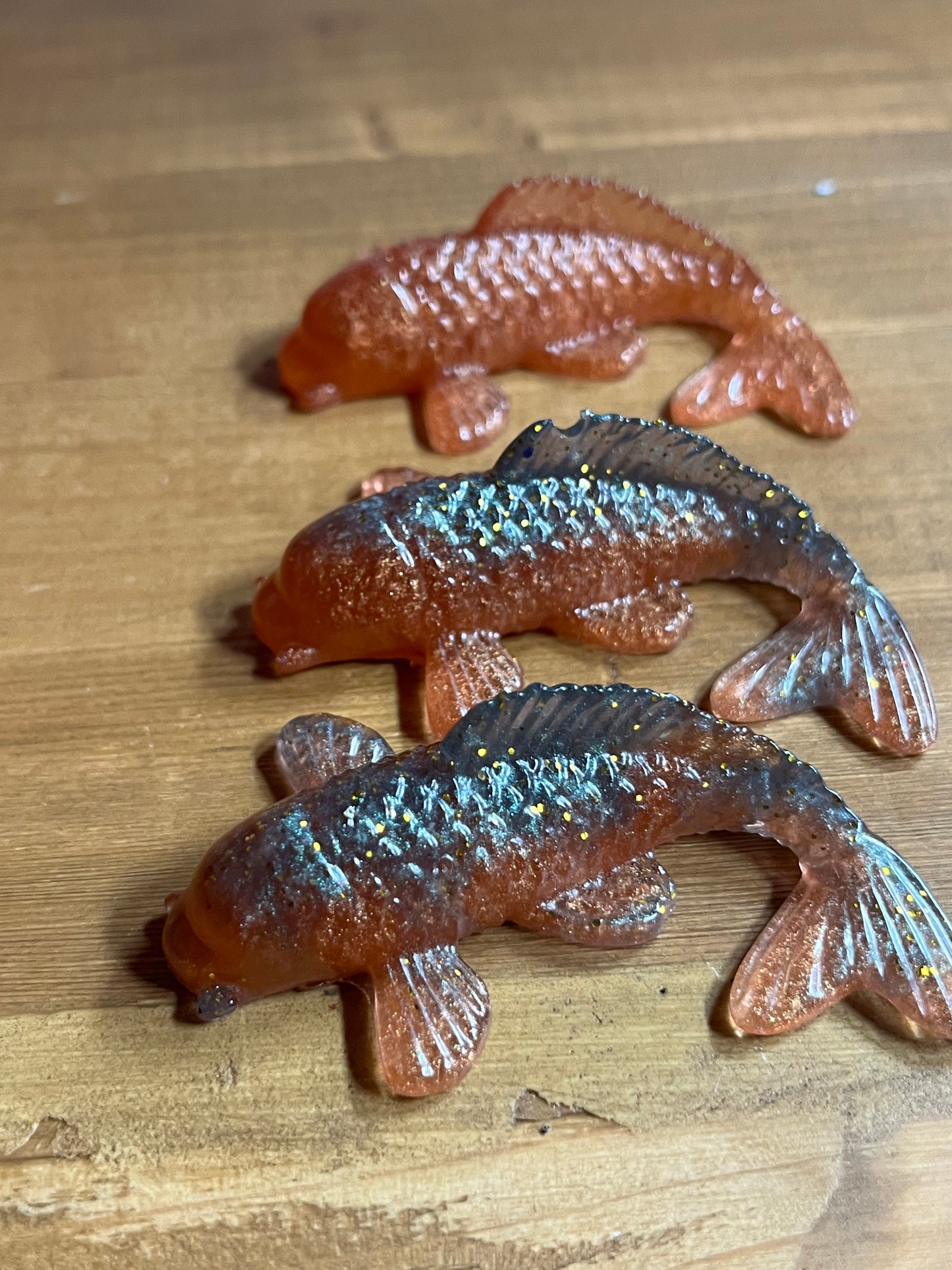 Three resin fish figurines on a wooden surface