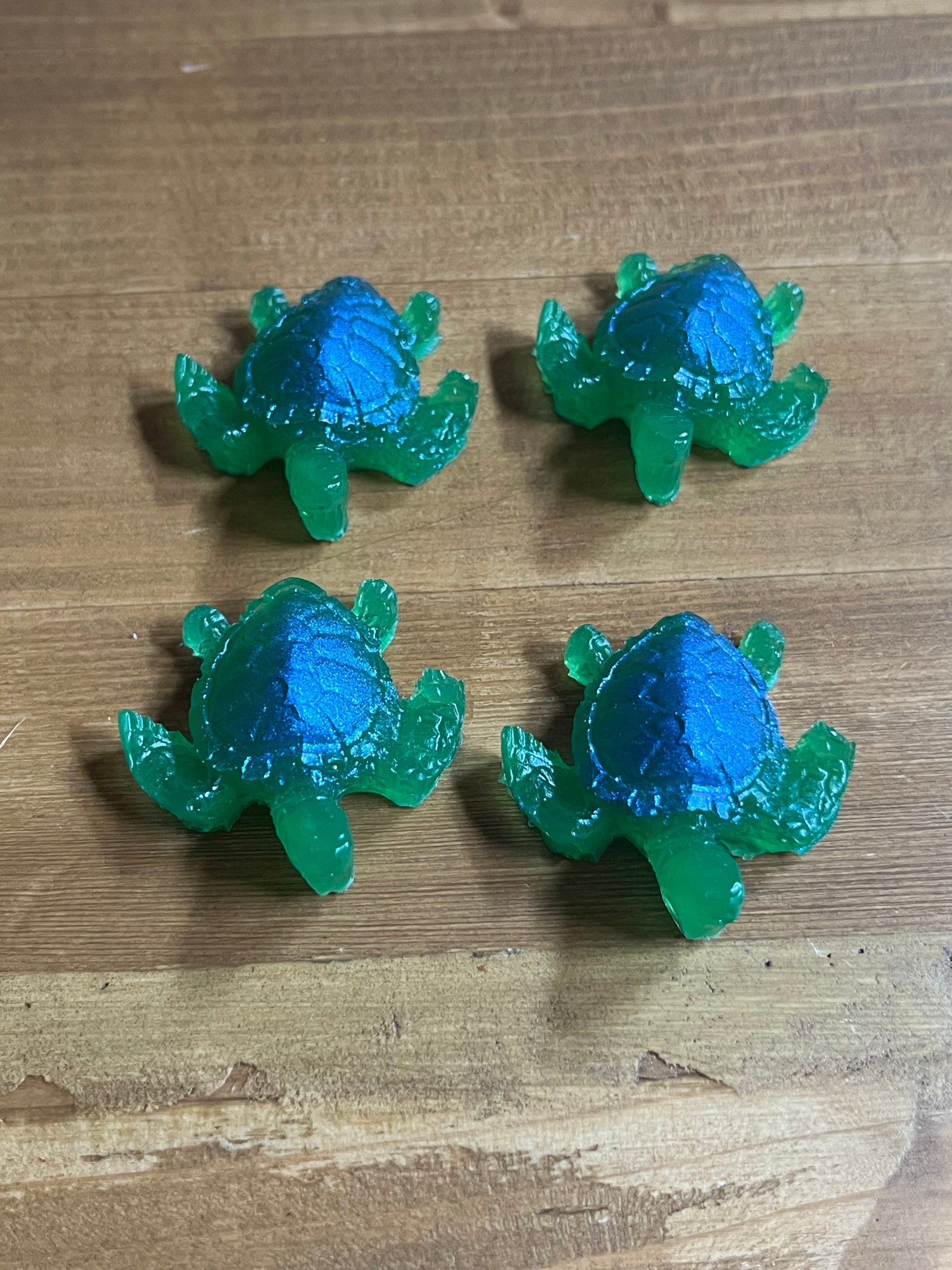 Four green and blue turtle figurines on a wooden surface