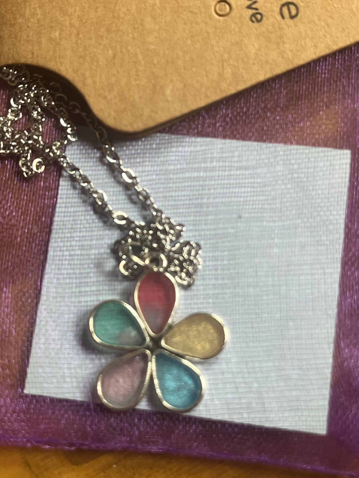 Floral pendant necklace on a display card with a brown background