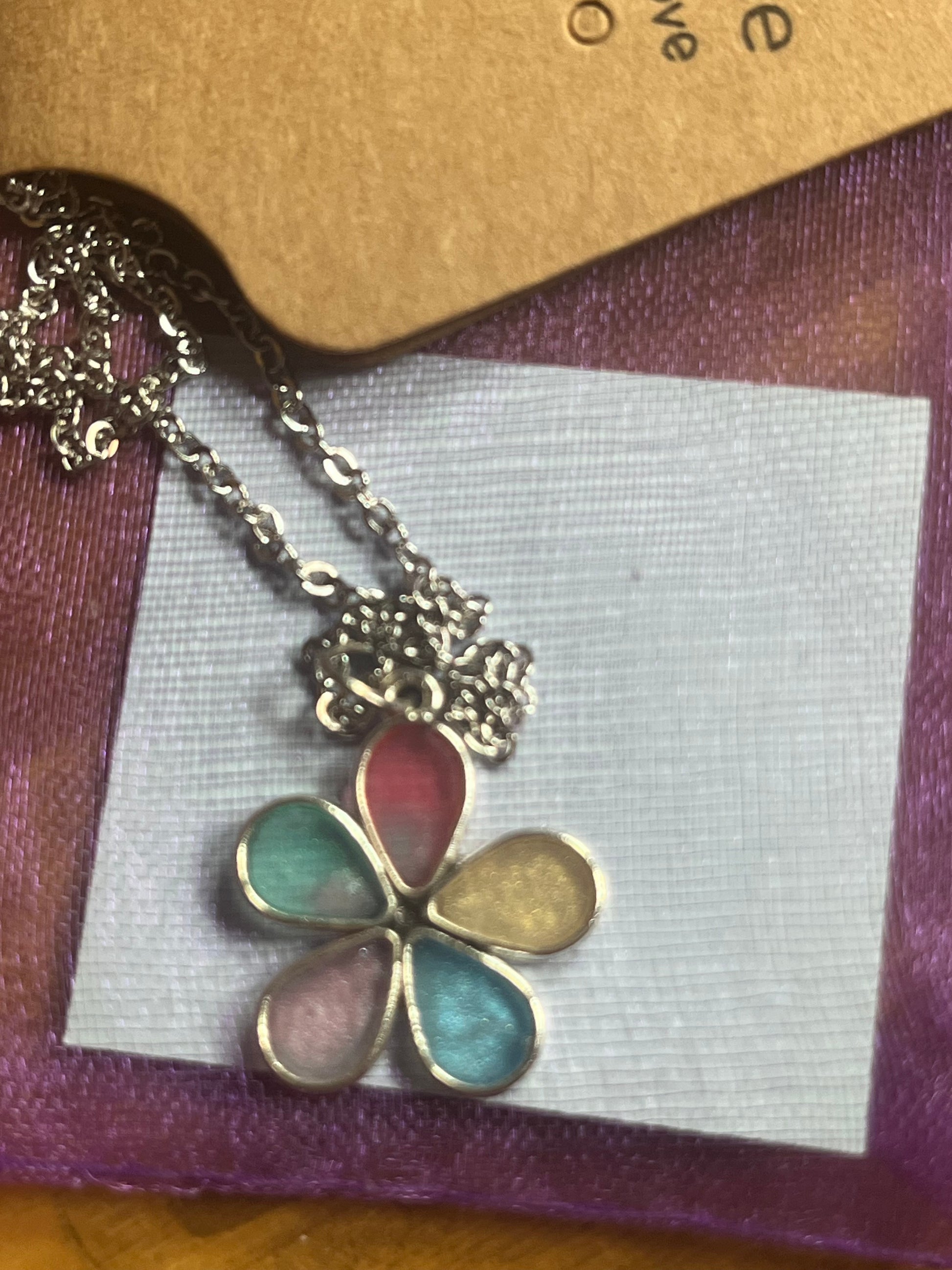 Floral pendant necklace on a display card with a brown background