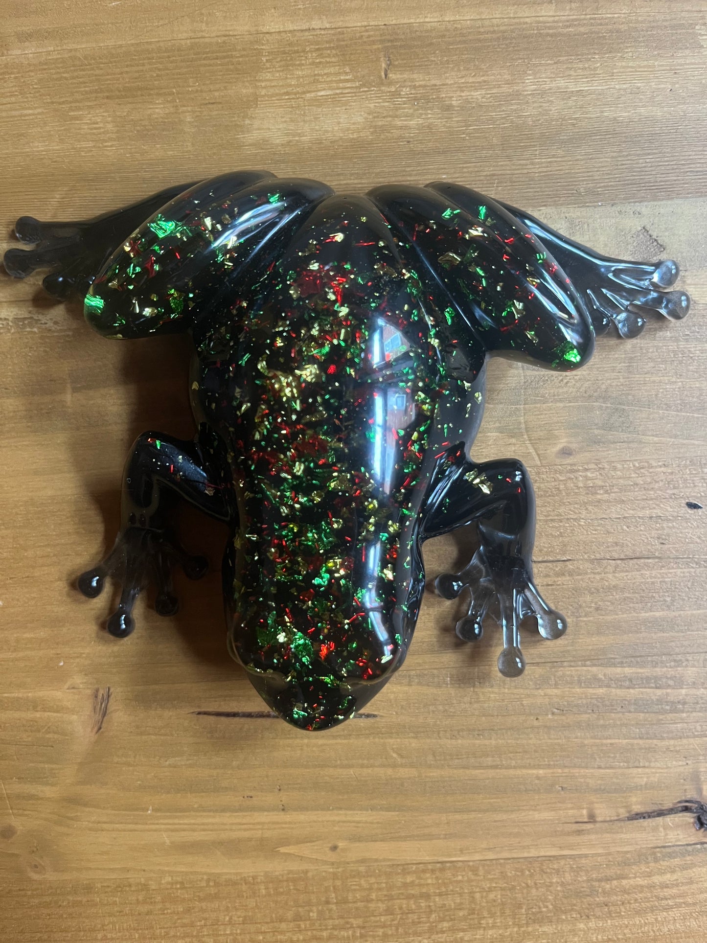 Decorative resin frog with multicolored speckles on a wooden surface
