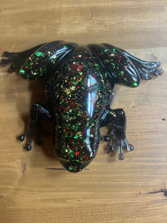 Decorative resin frog with multicolored speckles on a wooden surface